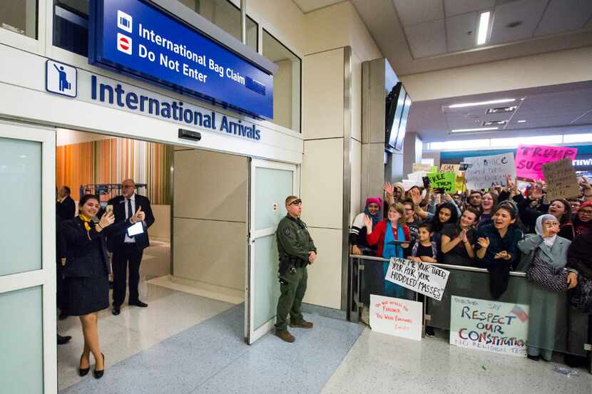 A flight crew member gives a thumbs up to protestors in the international arrivals hall at...