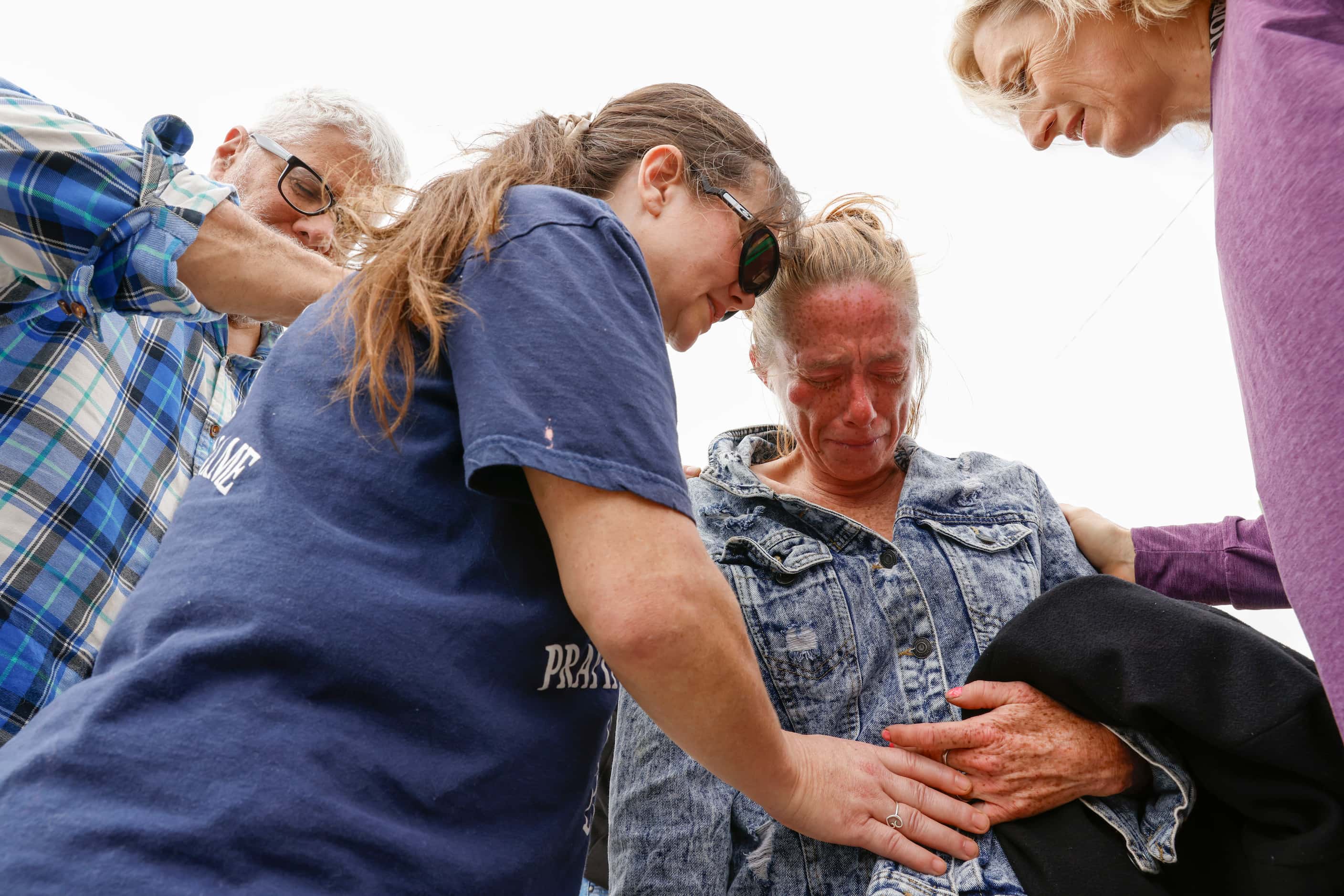 Andrea Ribera (center left) and Suzan Smeed (right) of Four Winds Ministry pray for the...
