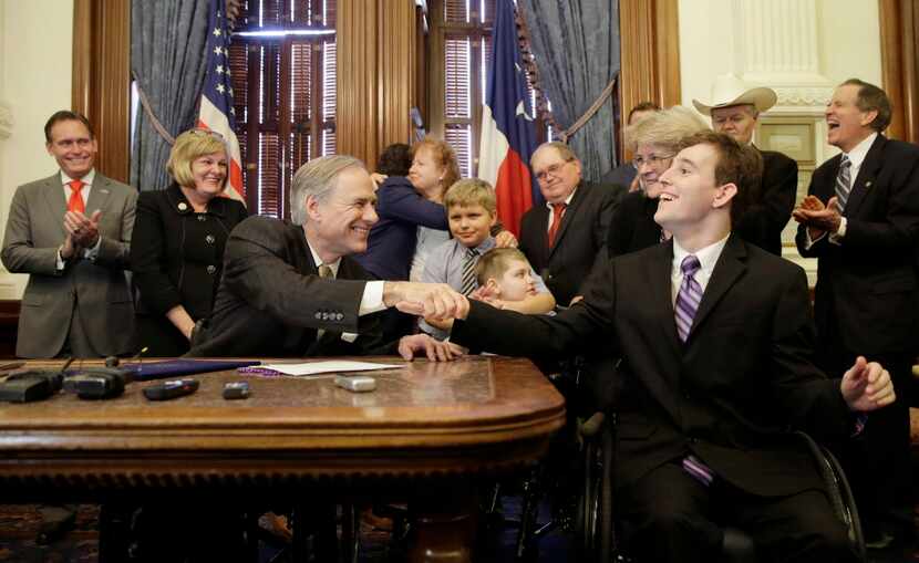 Texas Gov. Greg Abbott, front left, shakes hands with Zachariah Moccia, right, who has...