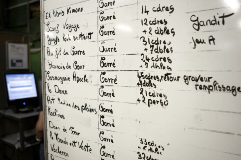 A dry-erase board shows the day’s printing schedule.