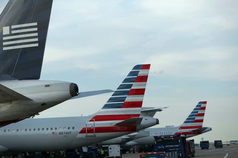 American Airlines jets — and one still painted with the US Airways logo (far left) — wait at...