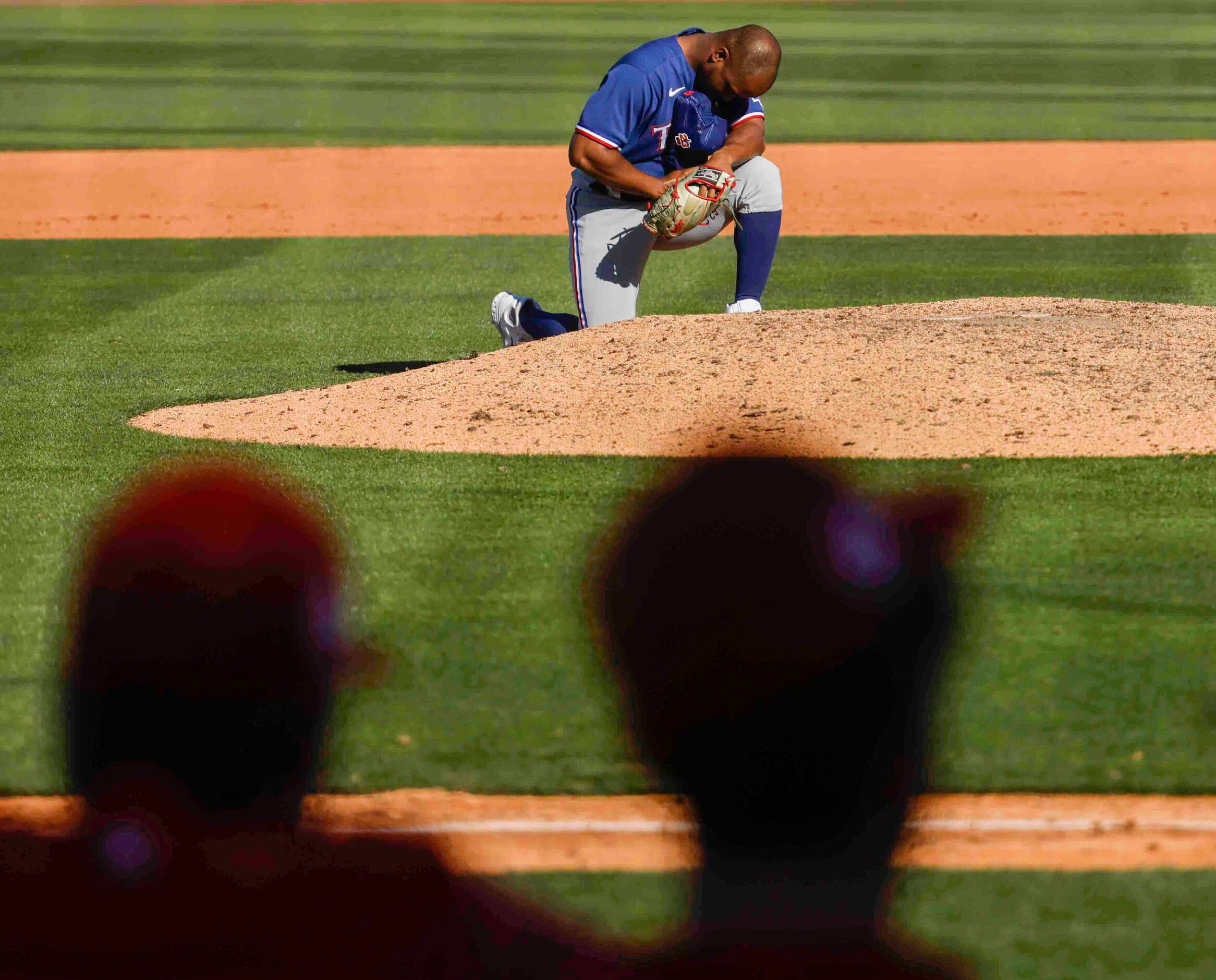 Texas Rangers pitcher Fernery Ozuna kneels before the pitcher’s mount during the ninth...