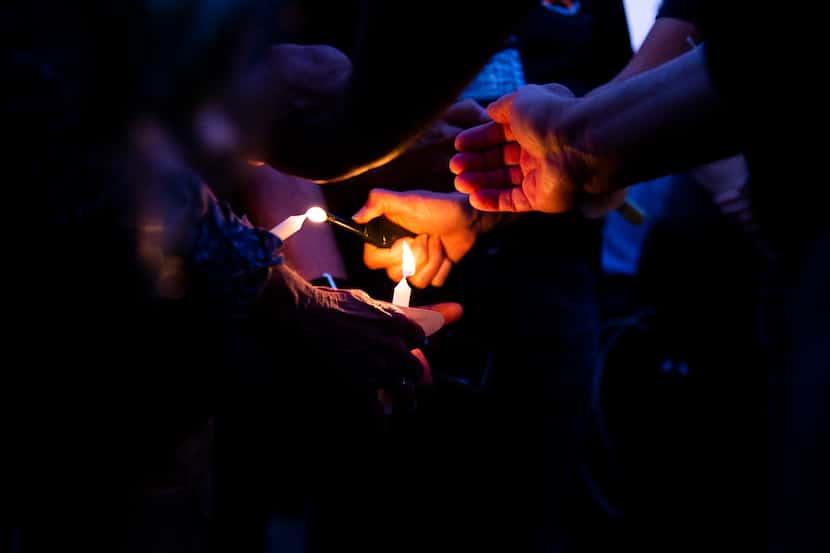 Attendees try to light candles at a vigil Sunday at the Grand Prairie Public Safety Building...