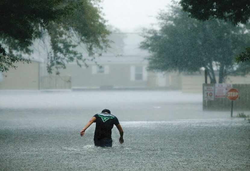Wading through floodwaters in Hurricane Harvey's aftermath, a man heads back to the...