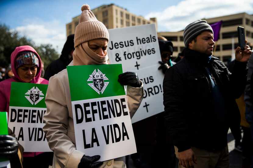 Julia Montiel (center) and other demonstrators pray and hold signs at a rally after marching...
