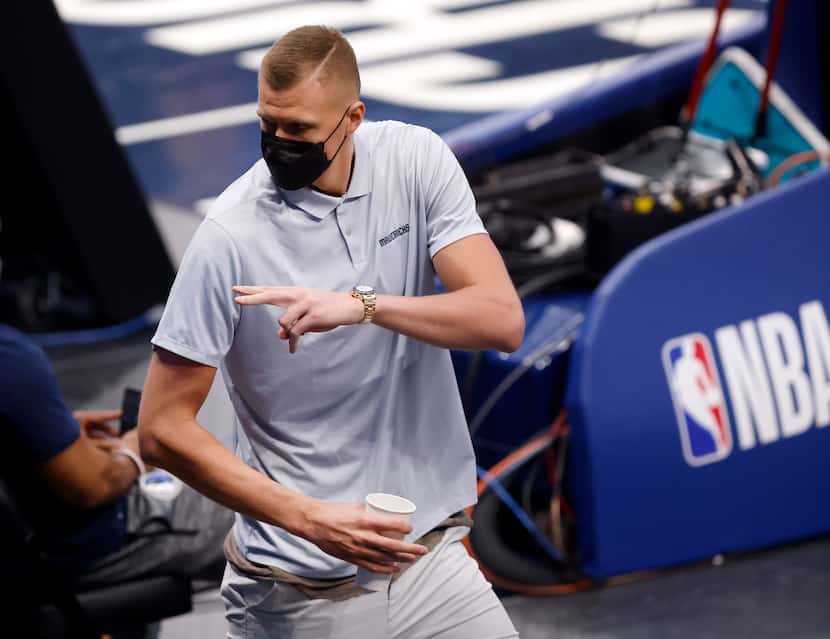 Dallas Mavericks injured center Kristaps Porzingis waves to friends as he steps into the...