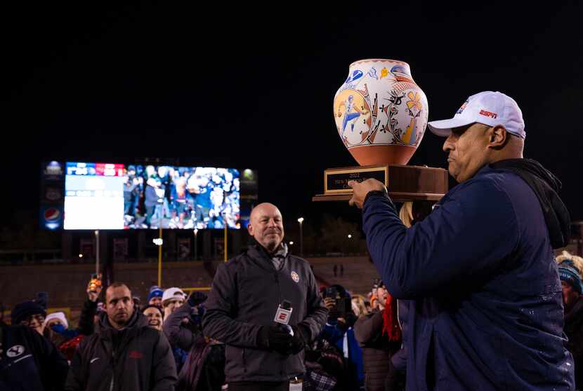 BYU head coach Kalani Sitake, right, holds the trophy during celebrations the team's victory...