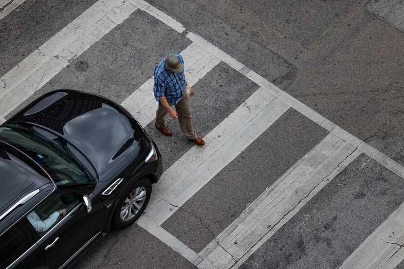 A man crosses S Pearl Expressway adjacent to Main St. after a car stops at a stoplight on...