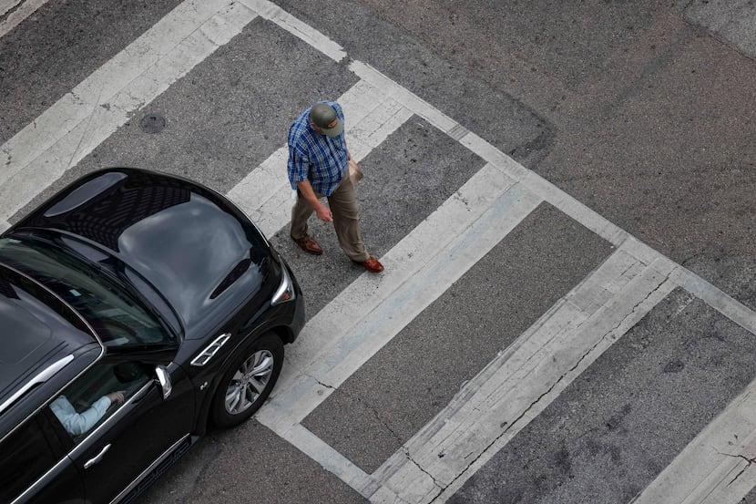 A man crosses S Pearl Expressway adjacent to Main St. after a car stops at a stoplight in...