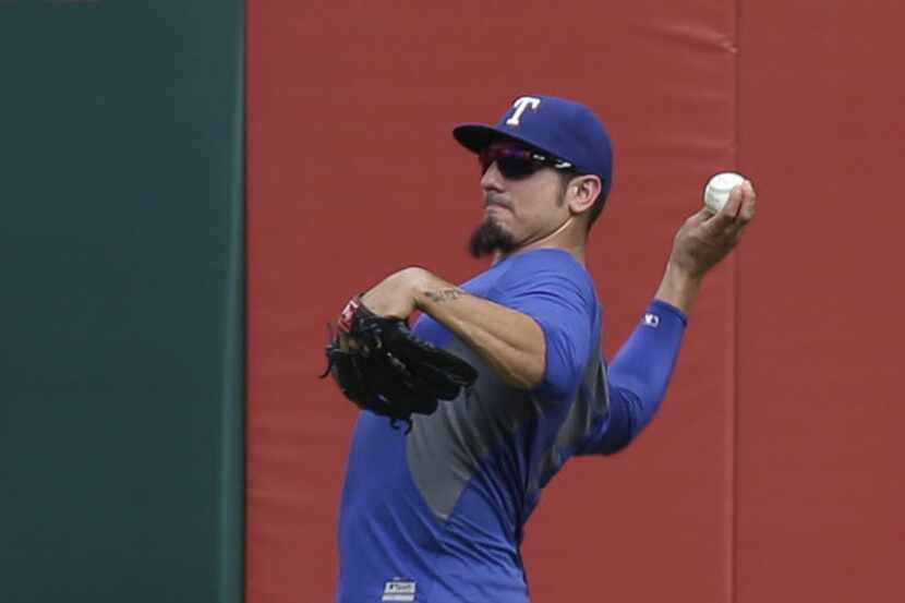 New Texas Rangers pitcher Matt Garza tosses a ball in the outfield during batting practice...