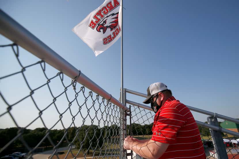 Argyle volunteer Mike Shandley puts flags int the stands prior to the Argyle-Decatur high...