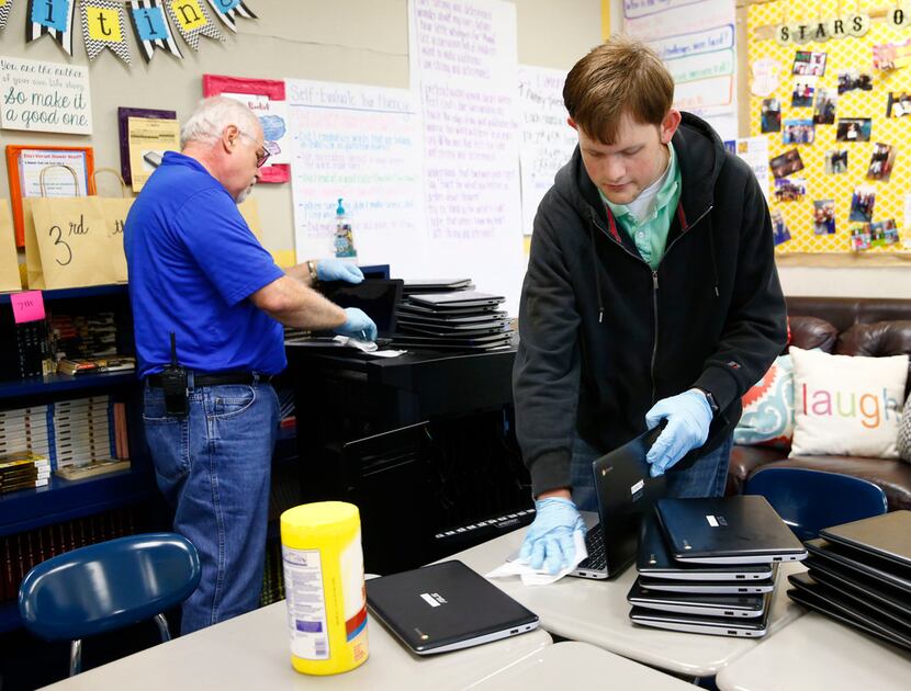 David Withrow (left) and Andrew Wilson with the IT department clean laptops in the...