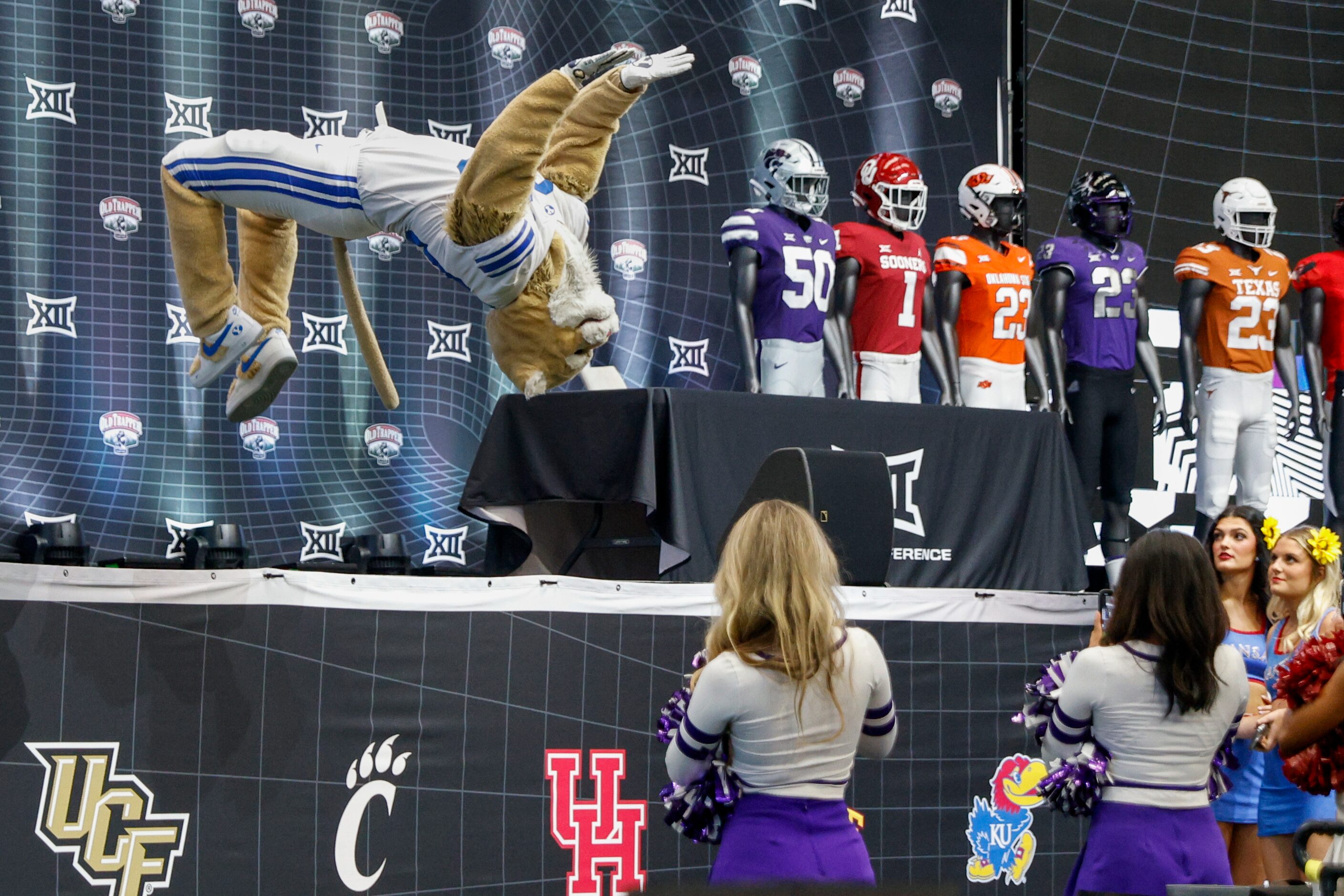 BYU mascot Cosmo the Cougar performs a backflip off the stage as cheerleaders watch during...