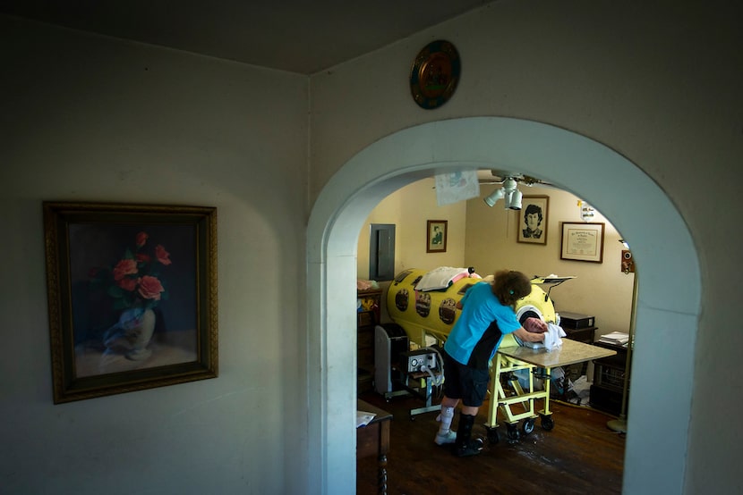 Caregiver and friend Kathryn Gaines washes the face of Paul Alexander beside his iron lung...