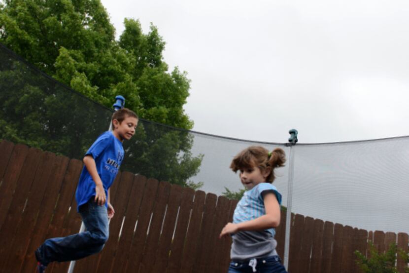 Emma Sayre, 7, and her brother Ethan, 9 play on the trampoline in the family's backyard in...