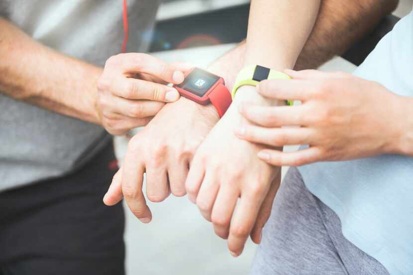 Sharing exercise performance. Active and sporty couple looking at their smartwatches and...