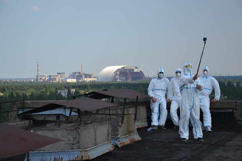 Visitors take a rooftop selfie with the Chernobyl nuclear power plant in the background.