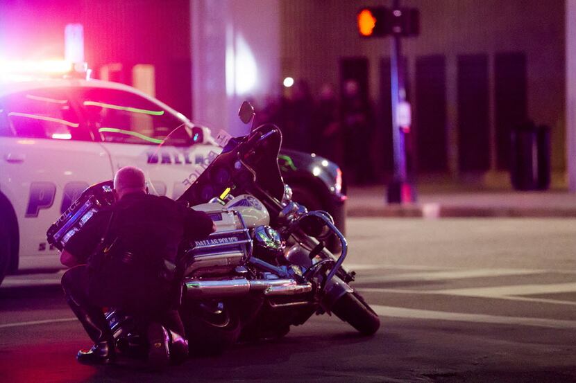 A Dallas officer took cover behind a police motorcycle during the sniper attack. (Smiley N....