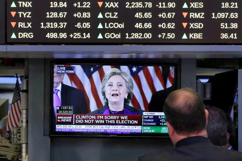 Traders watch Hillary Clinton's speech on a television screen on the floor of the New York...