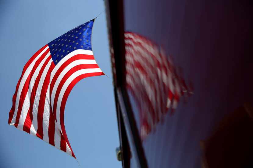 A flag of the United States of America flies between two Dallas Fire-Rescue engines after...