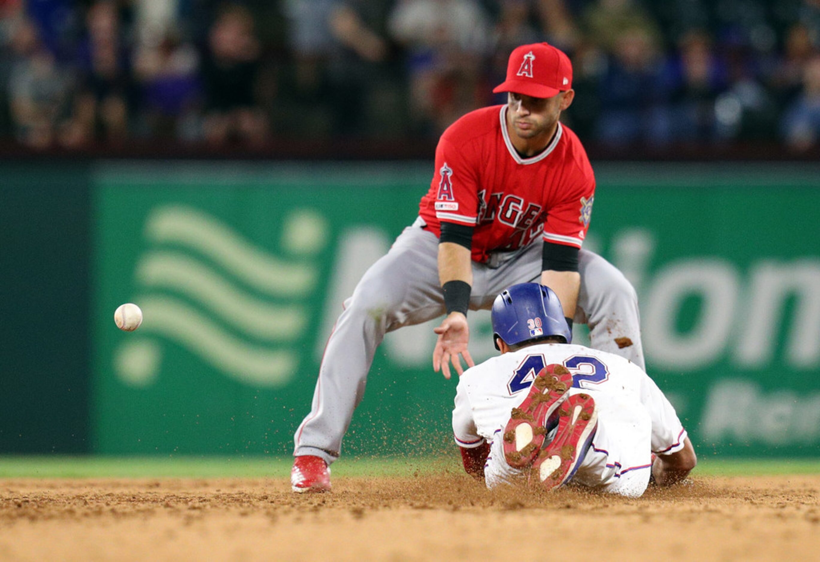 ARLINGTON, TEXAS - APRIL 15: Nomar Mazara #30 of the Texas Rangers dives safely back to...