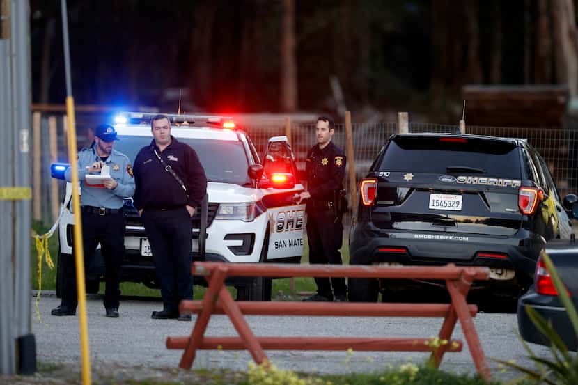 San Mateo County Sheriffs officers and EMS personnel gather along a road at a location near...