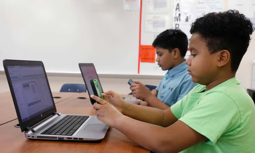 Sixth-graders Hemant Pacha (left), 11, and Mikey Shands, 11, work on their phones and...
