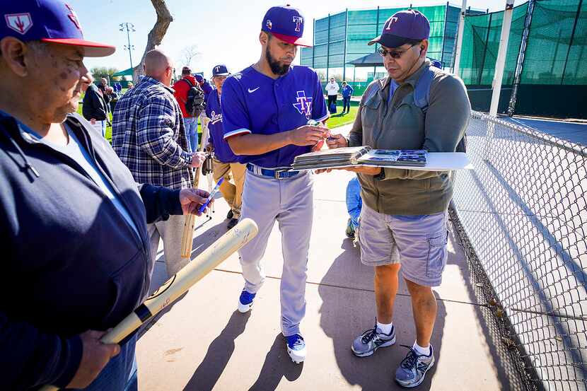 Texas Rangers catcher Robinson Chirinos signs autographs for fans before the first spring...