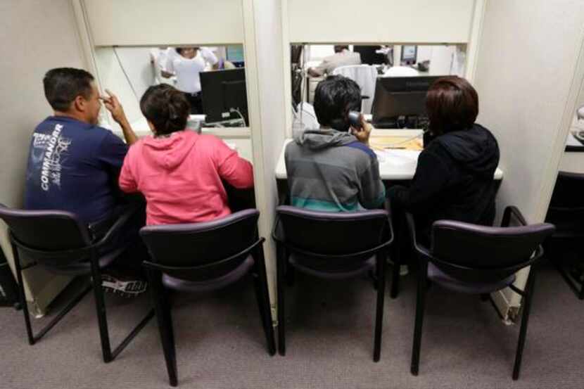 
People use a a phone bank to sign up for health care insurance at the business office of...
