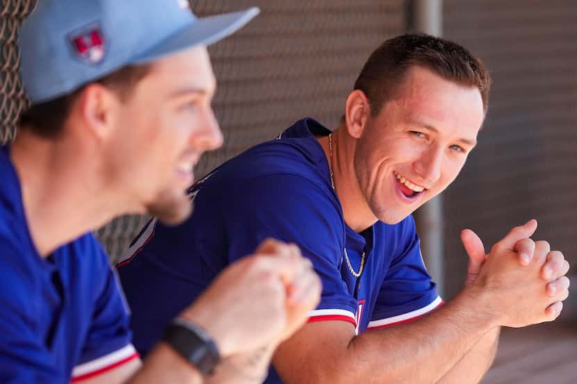 Texas Rangers outfielder Wyatt Langford laughs while chatting in a dugout with Evan Carter...