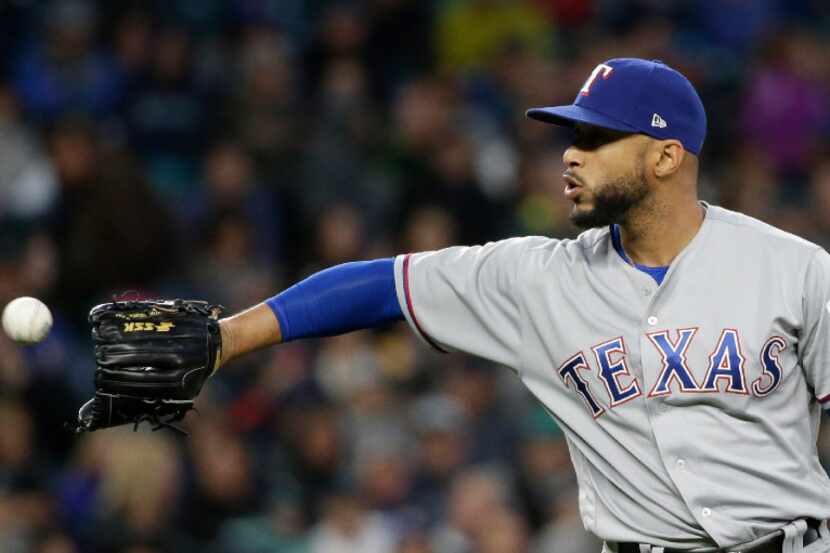 Texas Rangers relief pitcher Dario Alvarez reaches for a ball against the Seattle Mariners...