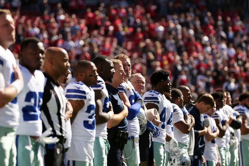 The Dallas Cowboys stand for the singing of the United States National Anthem before a...