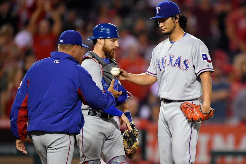 Texas Rangers starting pitcher Yu Darvish, right, of Japan, is taken out of the baseball...
