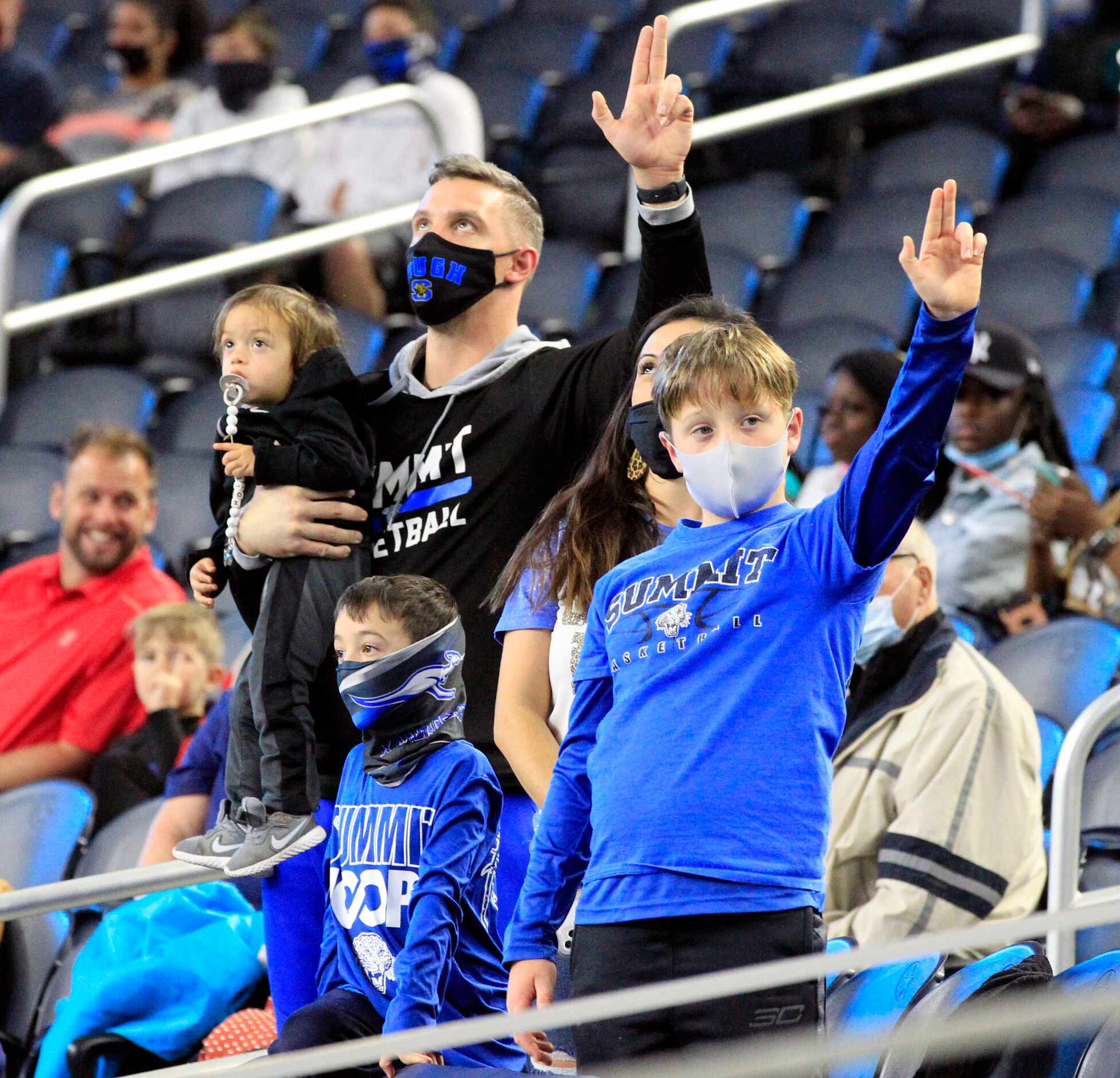 A family of Mansfield Summit fans hold their hands high during the school’s song before the...