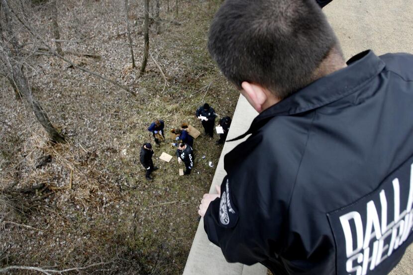A Dallas County sheriff’s deputy  watched a forensics team collect evidence where the bodies...