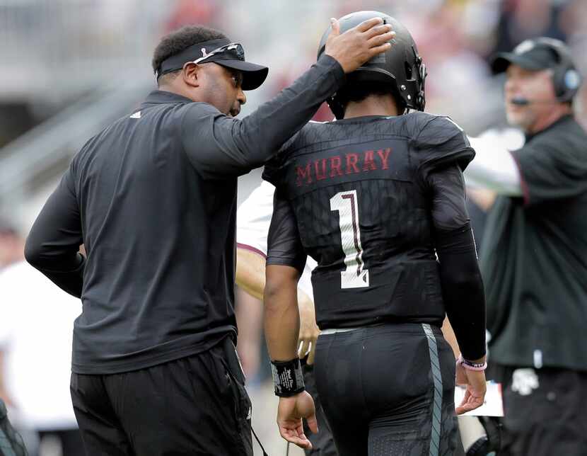 Texas A&M head coach Kevin Sumlin, left, pats quarterback Kyler Murray (1) as he walks off...