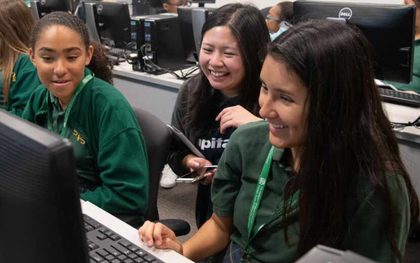 Three young female students participate in Innovate(her) while sitting in front of a computer.