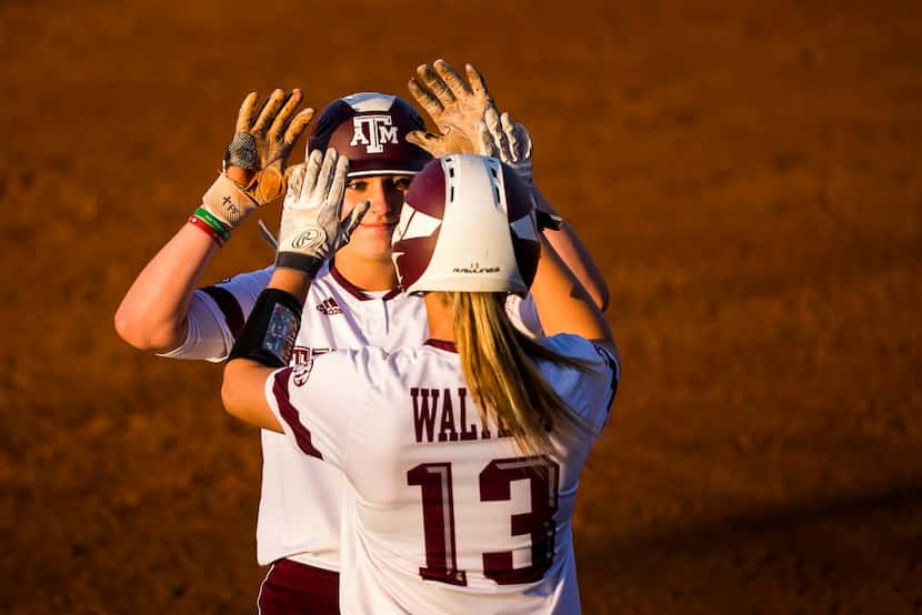 Texas A&M outfielder Sarah Hudek celebrates with catcher Ashley Walters after driving in two...