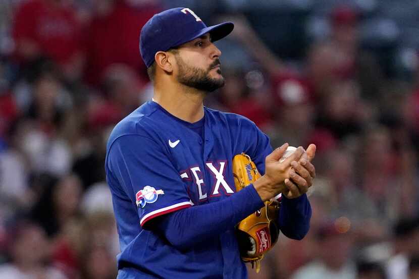 Texas Rangers starting pitcher Martin Perez rubs the ball after giving up a double to Los...