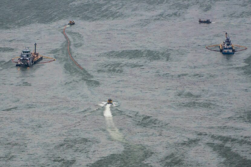 Vessels worked with skimmers and oil containment booms in Galveston Harbor on Sunday.