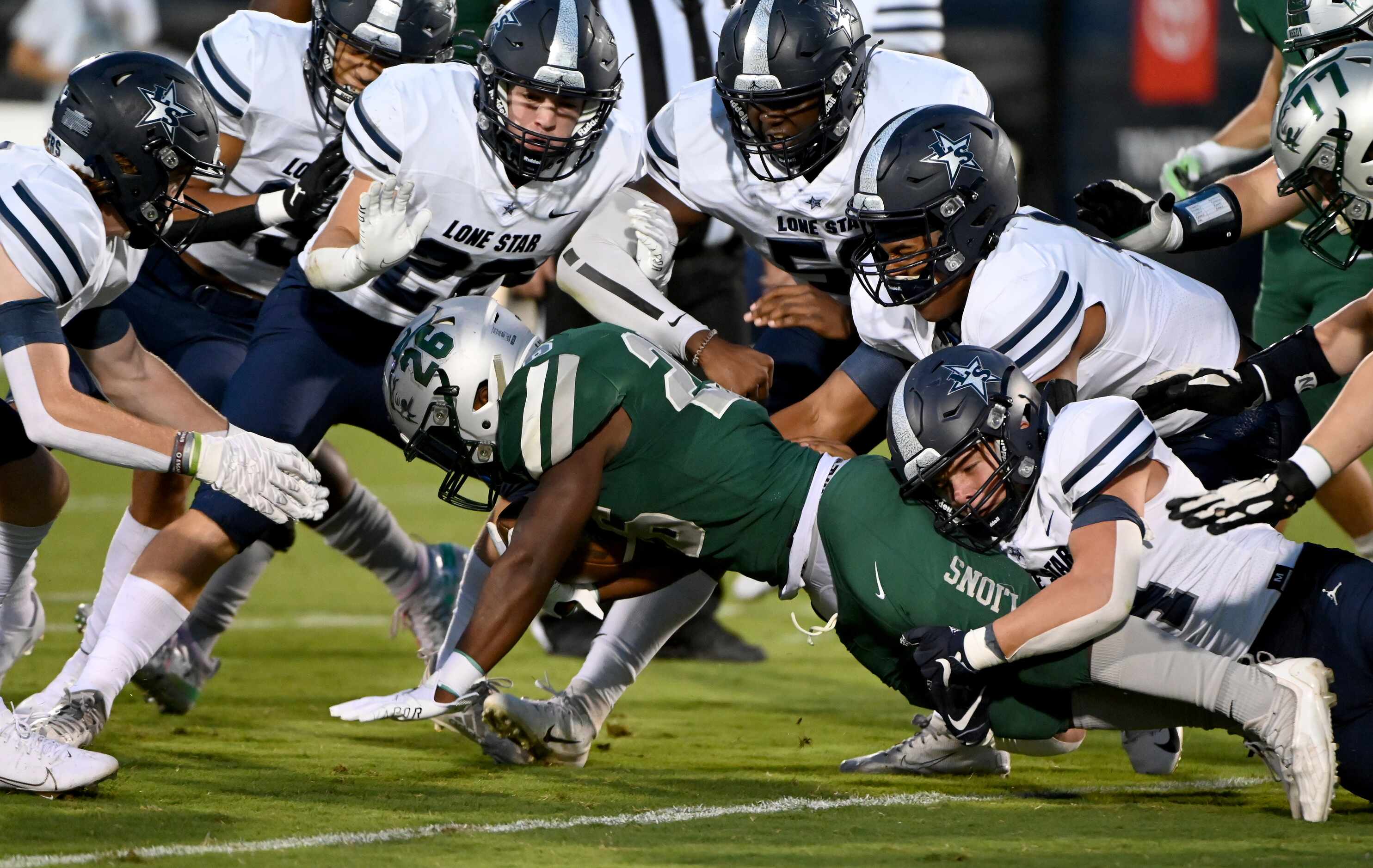 Frisco Lone Star’s defenders team up to tackle Frisco Reedy’s Aaron Daniels (26) in the...