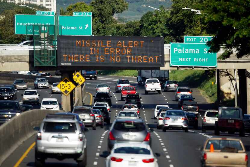 Cars drive past a highway sign that says "MISSILE ALERT ERROR THERE IS NO THREAT" on the H-1...