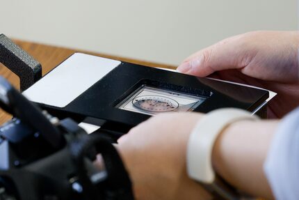 Front desk assistant Hilary Nguyen cuts out a photo of Anna Kern as she applies for a...