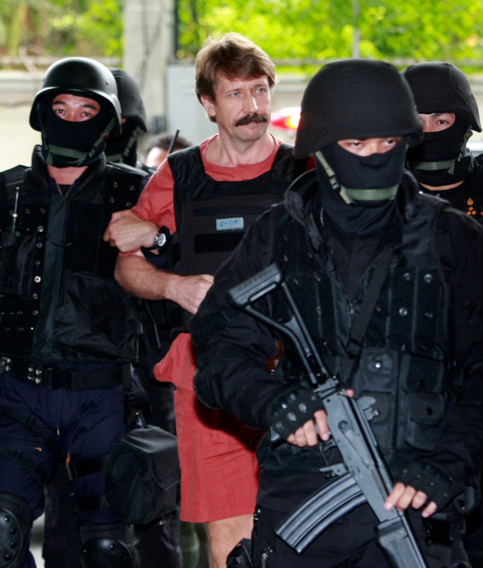 Suspected Russian arms smuggler Viktor Bout, center, is led by armed Thai police commandoes...