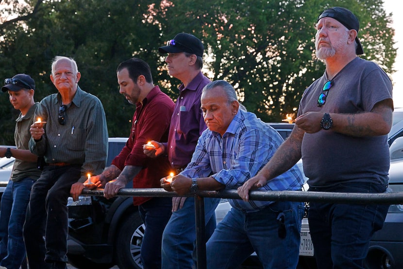 Marvin Thompson, right, and Jesus Gonzalez, second from right, hold candles for Robert...