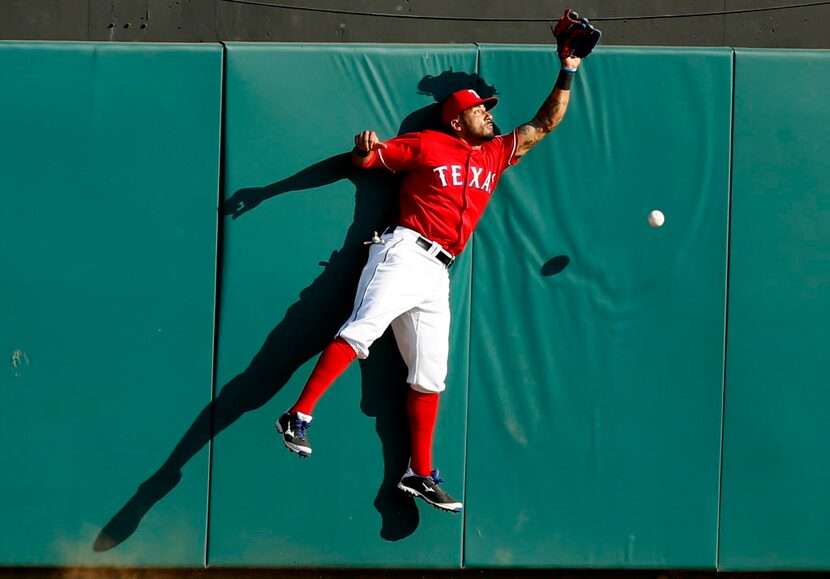 Texas Rangers center fielder Ian Desmond bounces off the outfield wall as he misses a deep...