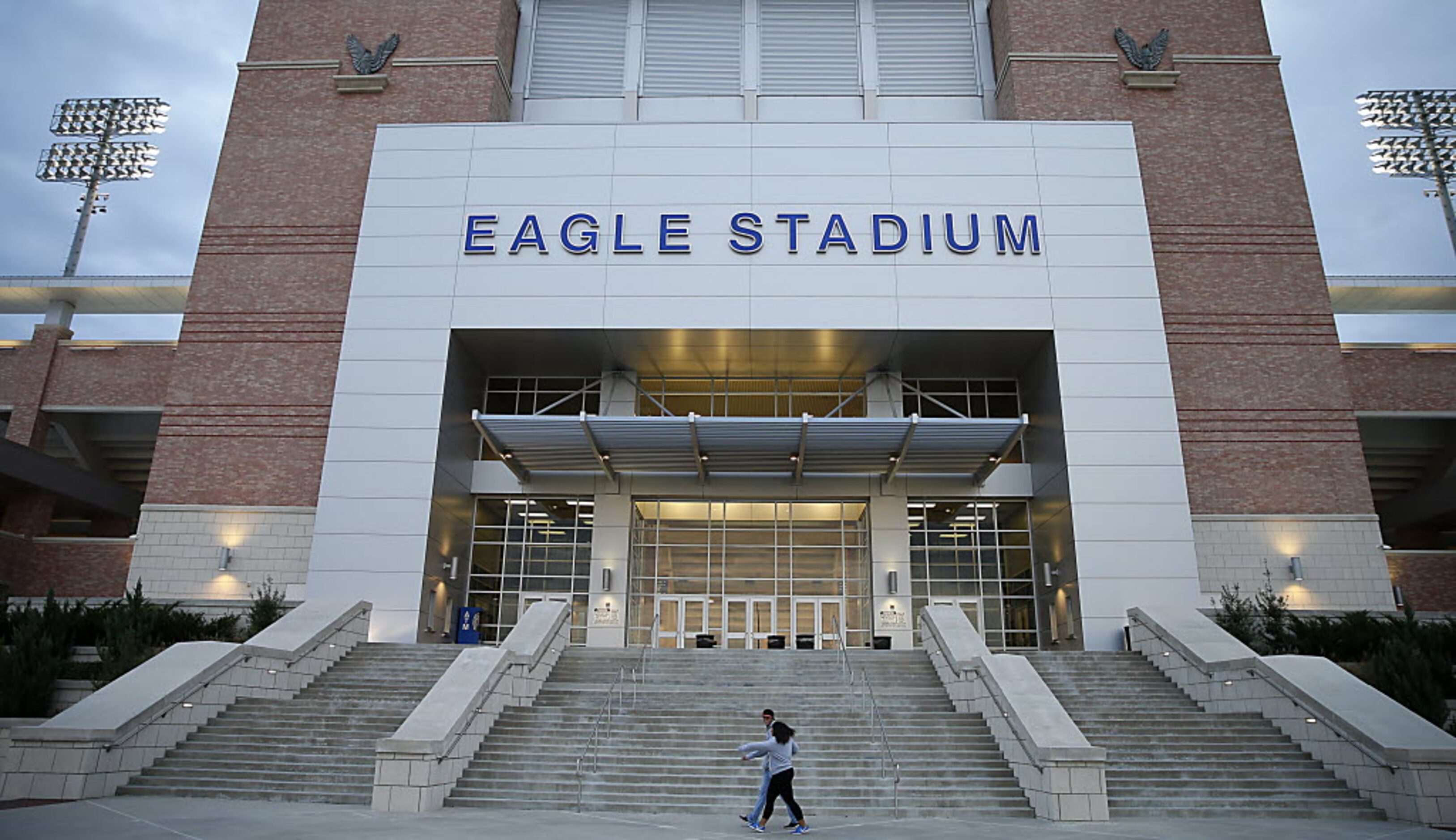 Two football fans walk by the Eagle Stadium prior to the Allen vs. Plano East game on...