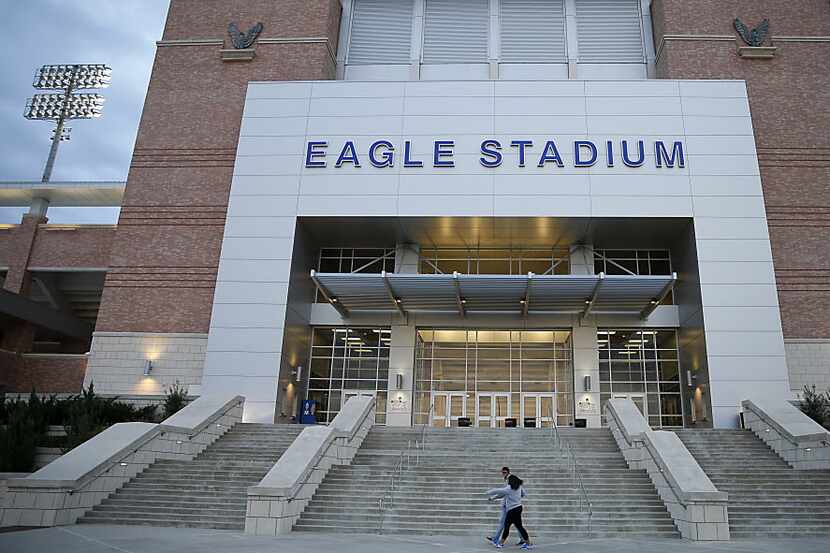 Two football fans walk by the Eagle Stadium prior to the Allen vs. Plano East game on...