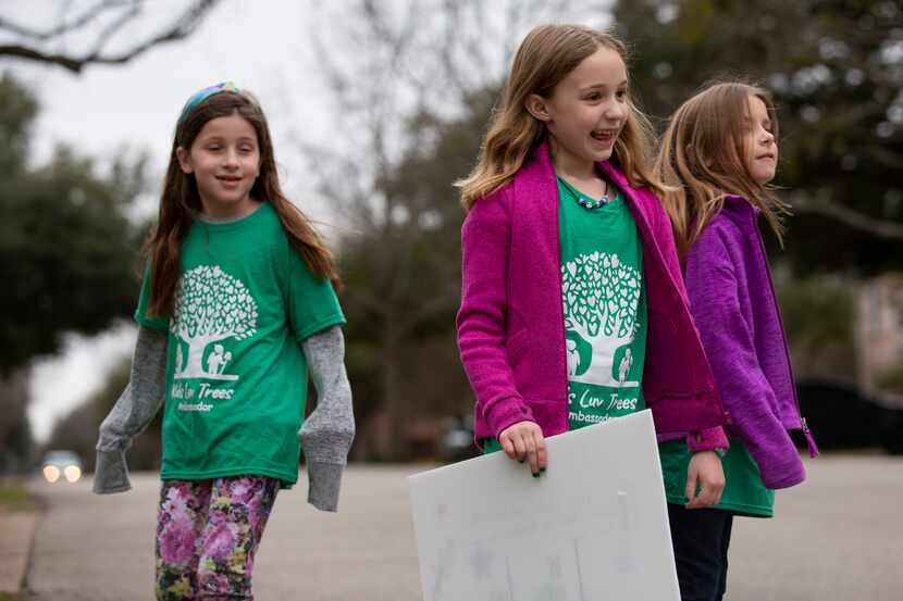 Violet Brister (from left), Brinley Smith and Zoey Reese walked down their street to put up...