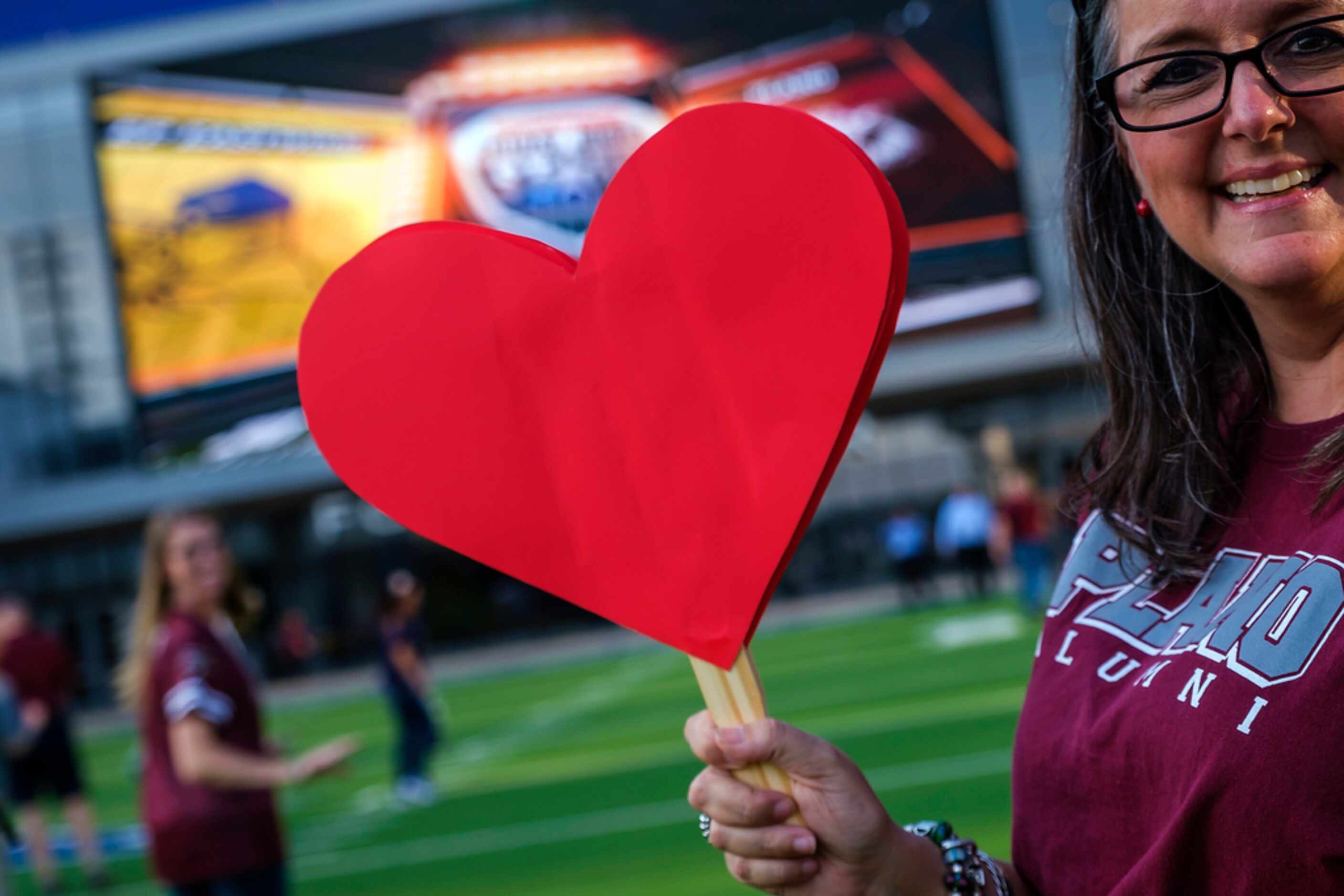 Plano High School alumnus Suzanne Wilson arrives at the game with cut-out hearts before a...